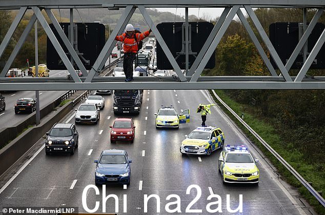 警察抵达,一名来自 Just Stop Oil 的激进分子占据了萨里戈德斯通附近 M25 公路上的龙门架