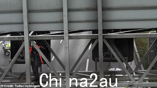 一个人站在 M25 上方的龙门架上星期一的 Just Stop Oil 抗议