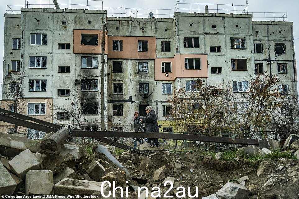 2022 年 11 月 9 日,乌克兰赫尔松省俄罗斯占领后最近解放的村庄阿尔汉赫尔斯克 (Arkhanhelske),几名妇女走在一座被毁坏的建筑物下