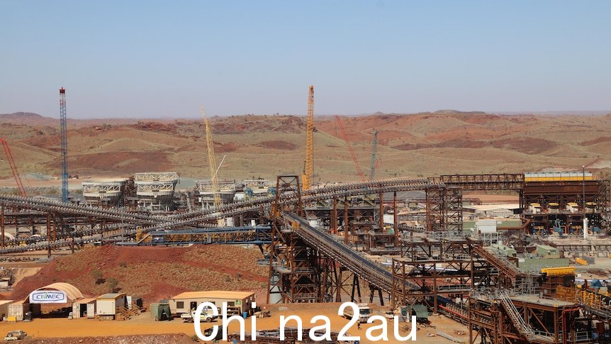 A photo of lots a giant equipment plant in the Pilbara, red dirt in front and behind it, blue sky above it.