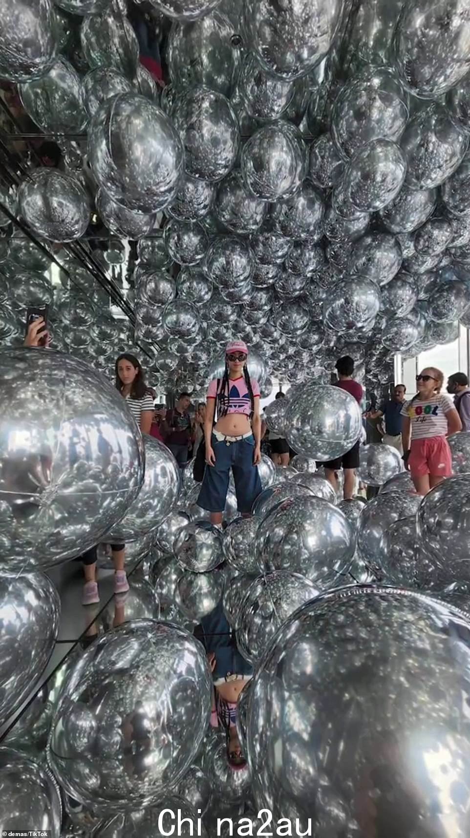 富有创意的摄影师在一个满是银色充气球的镜子房间里拍了一张女人的照片,然而背景中有几十个人,他们的倒影很混乱。