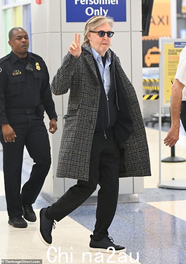 顺其自然!周五,80 岁的保罗·麦卡特尼爵士 (Sir Paul McCartney) 优雅地抵达纽约肯尼迪机场时亮出和平标志
