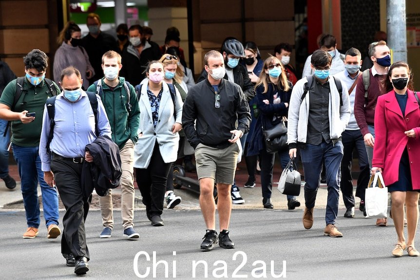 戴着口罩的人群穿过布里斯班中央商务区的十字路口。” /></p><ul class=