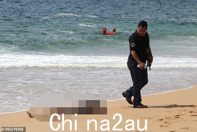 一名阿卡普尔科警官走过周日在伊卡科斯海滩冲上岸的一名男子的尸体