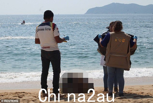 法医技术人员站在周日在墨西哥阿卡普尔科的伊卡科斯海滩发现的一名饱受折磨的男子的尸体附近