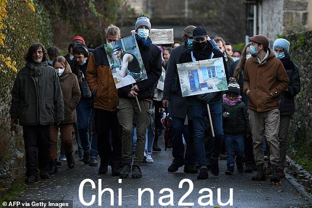 在这张拍摄于 2021 年 12 月 4 日的档案照片中,一位朋友拿着摩根基恩的肖像,他带领游行向这位年轻人致敬,一年后他被两名猎人杀害, Cajarc, south-western France