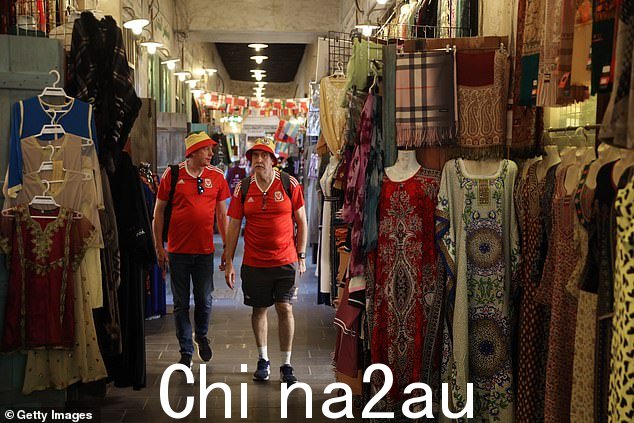 两名威尔士支持者在等待他们国家的首场比赛时穿过市场