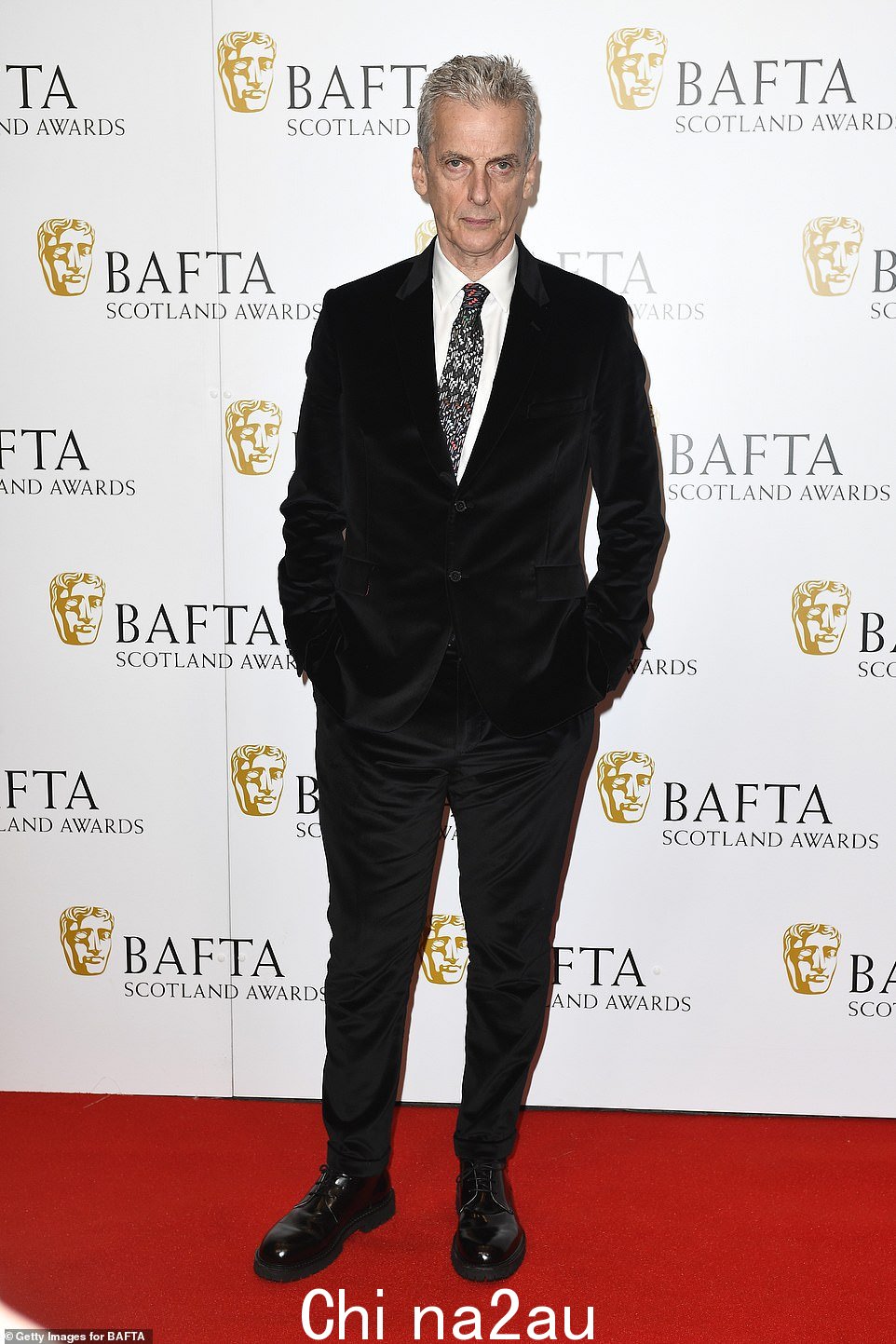 Peter Capaldi 周日晚上在红地毯上摆姿势时,穿着黑色天鹅绒西装和漂亮的皮鞋,显得衣冠楚楚
