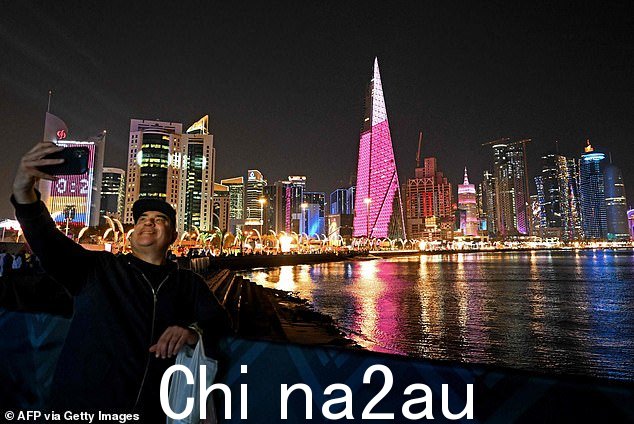 一名男子在 2022 年 11 月 20 日卡塔尔 2022 年世界杯足球赛期间在多哈的滨海大道拍照