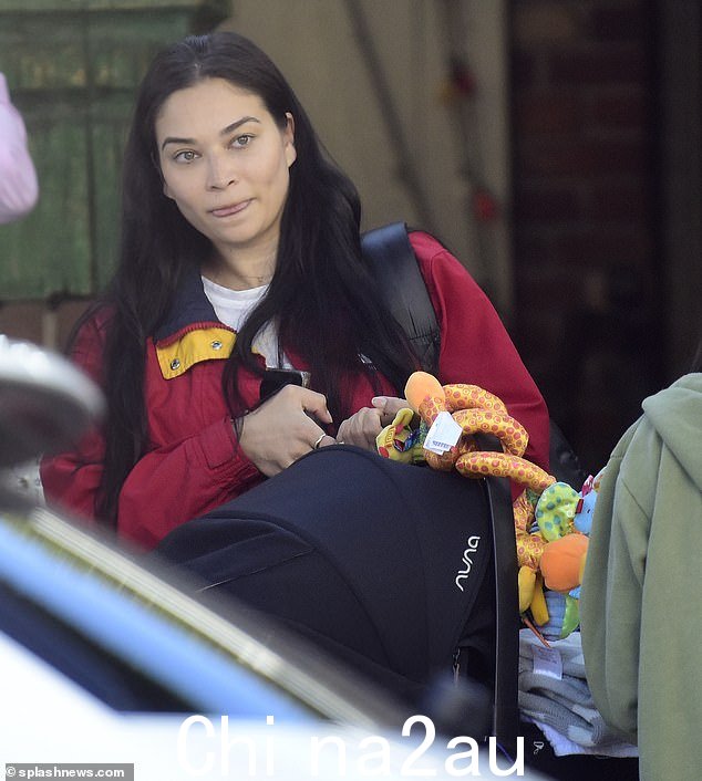 重负荷:婴儿依偎在妈妈携带的黑色汽车座椅内,看不到他