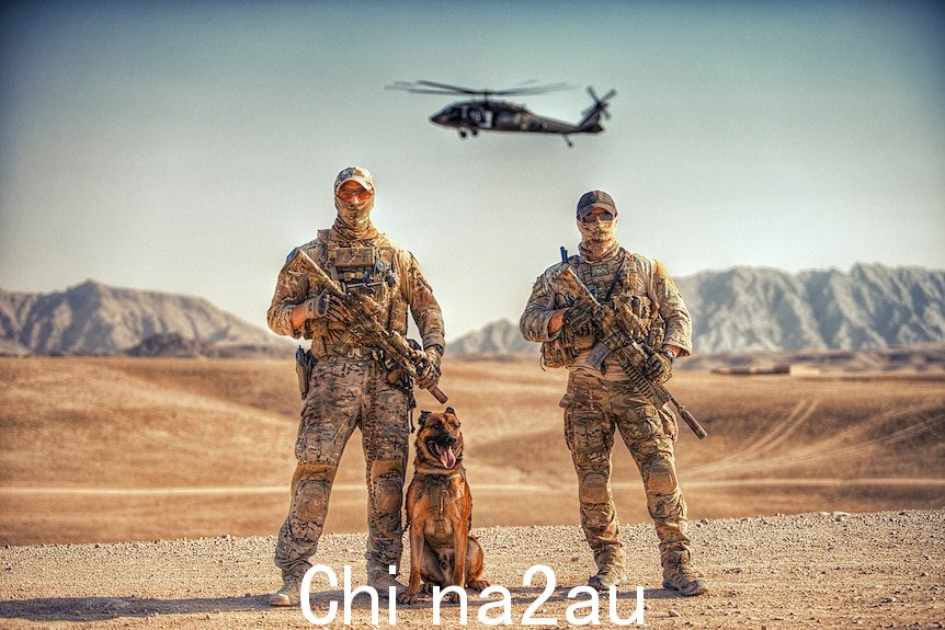 Two手持武器的士兵在沙漠中摆姿势，身后有一只狗和一架直升机盘旋