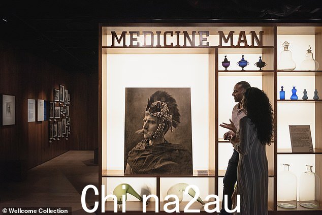 一男一女站在 Wellcome Collection 的“Medicine Man”展览中,照片中 Henry Wellcome 身着土著人的服装,身后” class=
