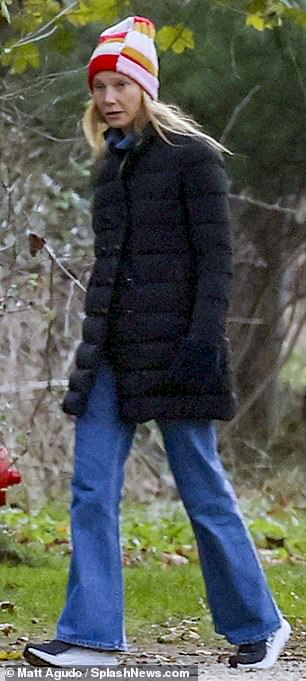 舒适:时尚企业家穿着黑色羽绒服、喇叭裤和运动鞋保暖