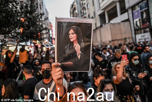一名抗议者在支持阿米尼的示威游行中举着玛莎·阿米尼的肖像,阿米尼是一名年轻的伊朗妇女,她于 9 月在德黑兰被伊斯兰共和国道德警察逮捕后死亡