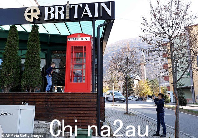 孩子们在哈斯市的新酒吧“Britain Resto Longue”旁边的英国电话亭里拍照留念