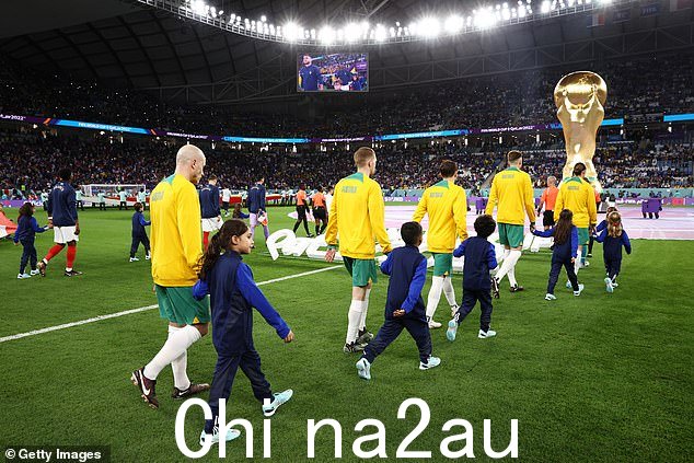 澳大利亚球员在 2022 年卡塔尔世界杯 D 组法国和澳大利亚之间的比赛前与护送孩子一起走进球场
