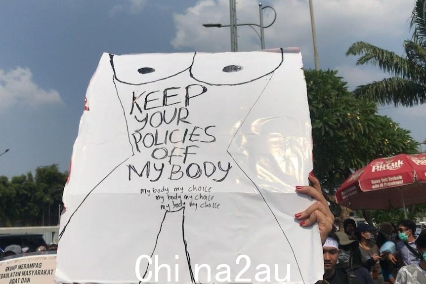 一名抗议者举着标语，上面写着''让你的政策远离我的身体'和'我的身体我的选择'。