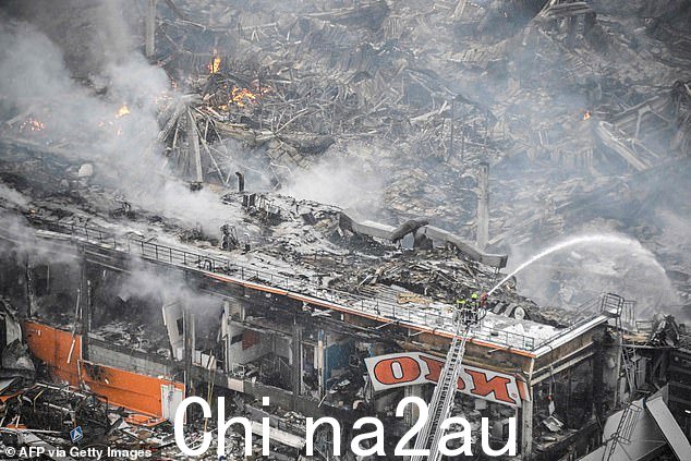 被毁的购物中心,被蹂躏的b y a flaming inferno, is seen this morning firefighters continue to battle the blache
