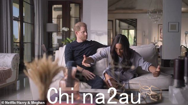 梅根似乎行了一个非常夸张的屈膝礼,讲述她第一次见到女王时的情景,而她的丈夫哈里则在一旁观看