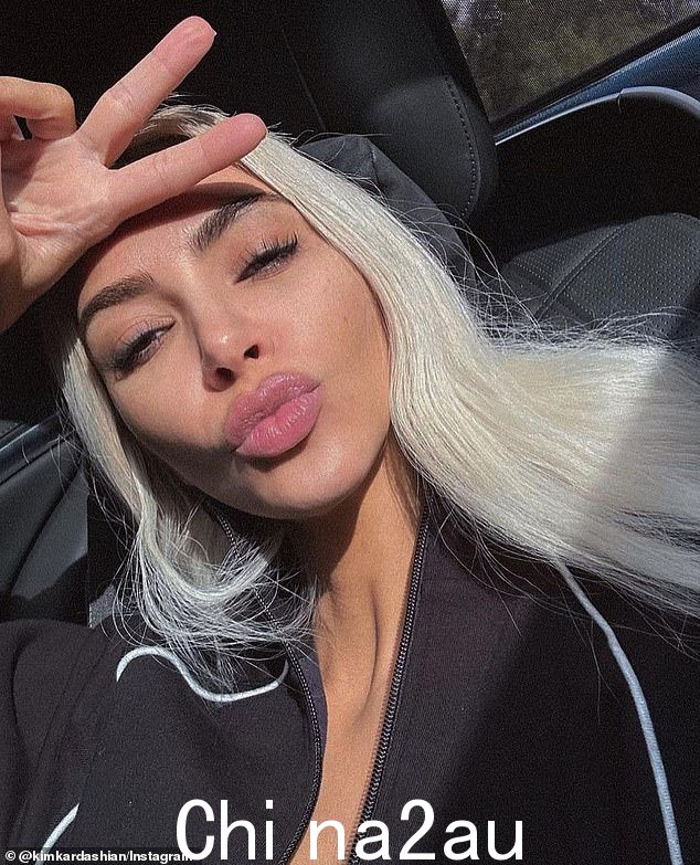 多么棒宝贝:Kim Kardashian 吹了一个吻,在后座上用她的白金色长发披散在肩上扔了一个和平手势。