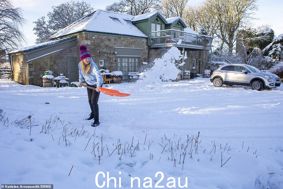 周日大雪过后,一名妇女在西洛锡安的凯恩斯农场水库铲雪