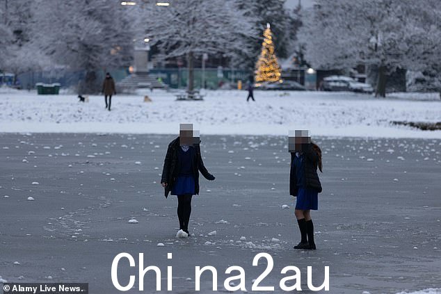 女学生冒着站在温布尔登冰冻池塘上的风险,因为伦敦是 bl anketed in snow