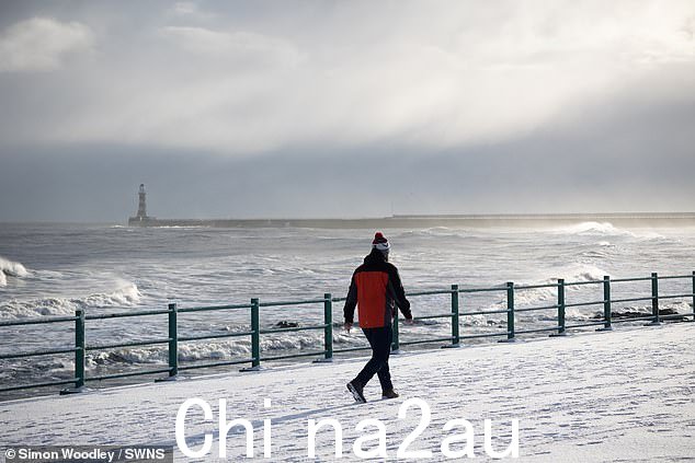 星期四,一个人在桑德兰的海滩边走过雪