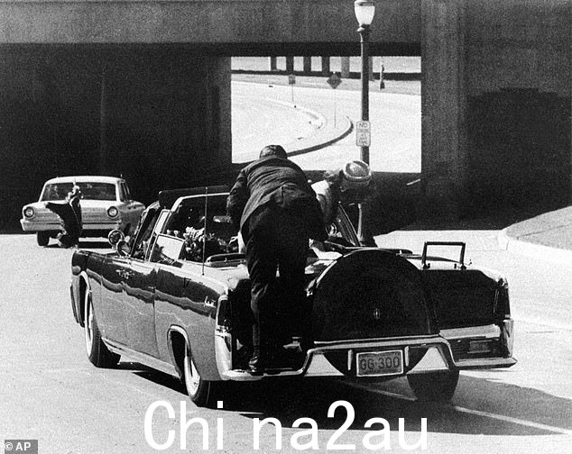 希尔先生被人看到是为了争先恐后而出名的第一枪打响后就保护了总统,但没有及时打到他身上。上图:当 Jackie Kennedy 试图爬出来时,保镖爬上豪华轿车的后部将她推倒