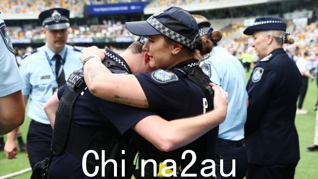 警察在 Gabba 互相安慰堕落的军官。图片：Chris Hyde - CA/Cricket Australia 来自 Getty Images