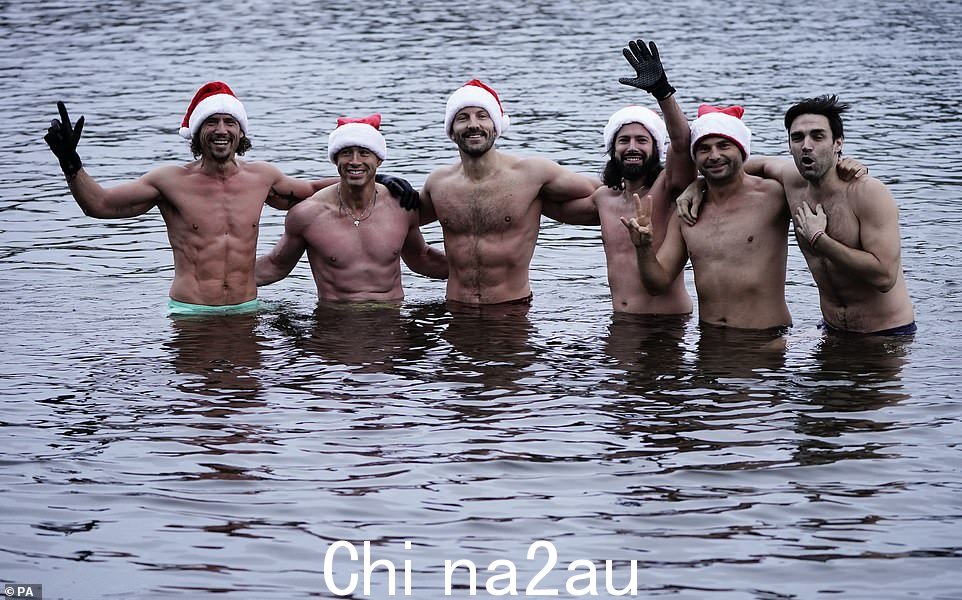 一群欢快的游泳运动员在伦敦海德公园的蛇形公园在一年一度的彼得潘杯比赛前戴着圣诞帽拍照留念