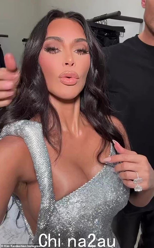 耀眼:Kim 拍摄自拍视频时,她的银色礼服在房间明亮的灯光下闪闪发光