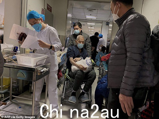 图:12 月 28 日,在中国东北的天津市第一中心医院,一名坐在轮椅上的 Covid 患者被转移
