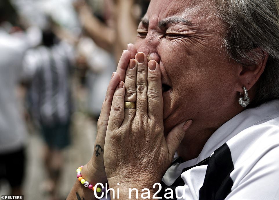 穿着桑托斯衬衫的女人无法控制自己的情绪,因为巴西继续哀悼其中之一s most famous sons