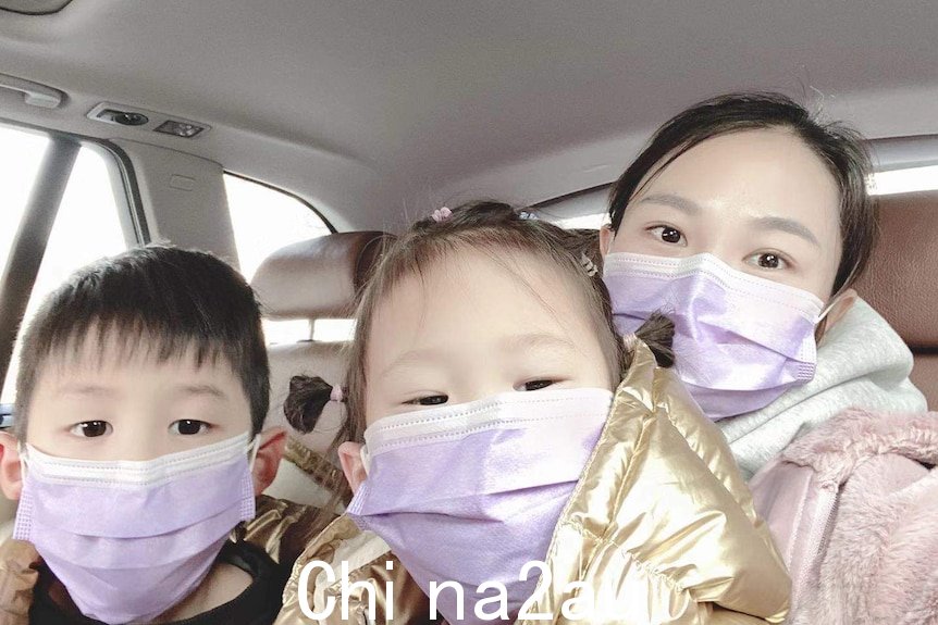 一名妇女和她的两个孩子坐在车里。他们都戴着防护口罩。