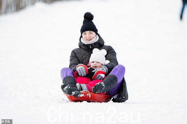 一个女人和她年幼的孩子享受一个地方在凯恩戈姆斯 (Cairngorms) 积雪覆盖的斜坡上滑雪橇的经历