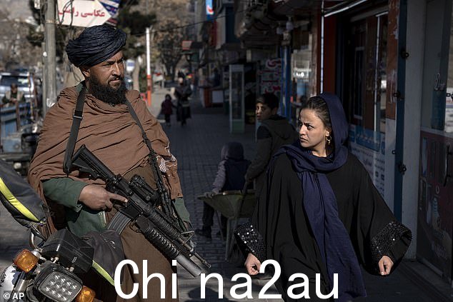 塔利班阴影下的生活:上个月,一名妇女从阿富汗喀布尔的一名武装警卫身边走过。照片中的妇女未参与本文
