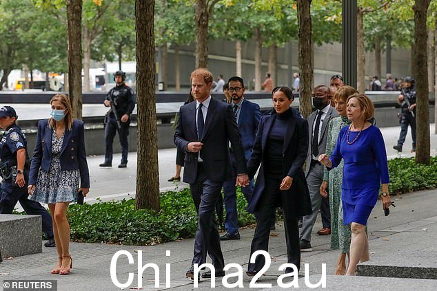 2021 年 9 月,在曼哈顿参观 9/11 纪念馆时,手持长枪的纽约警察局警官站在一旁看着苏塞克斯公爵和公爵夫人哈里和梅根走路