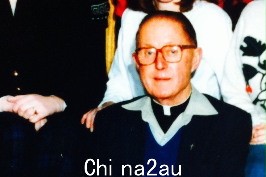 1992 年，Peter Searson 神父坐在班级合影前的椅子上。