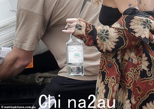 同时抓着 Casamigos 的瓶子——它是由乔治克鲁尼和兰德格伯创立的——伊莫金一只手拿着一个在另一个