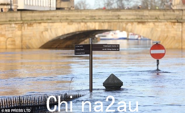 道路标志和围栏被水淹没,因为约克的乌斯河水位上升,救援队正在与洪水作斗争