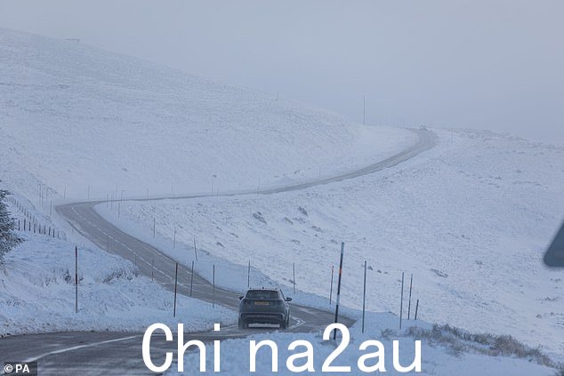 周日,一辆汽车驶过苏格兰高地凯恩戈姆山脉白雪覆盖的山丘