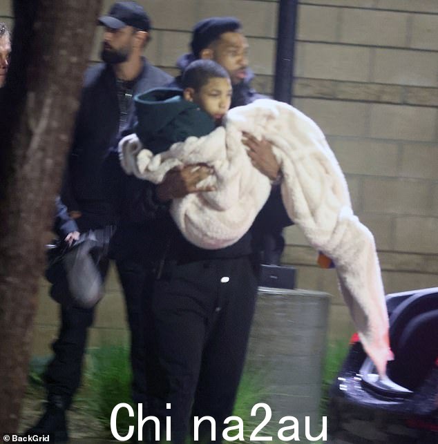 阴沉:特里斯坦,31 岁,穿着一身黑衣服,带着他裹着毯子的 16 岁弟弟阿马里,从金的私人飞机上到等候的 SUV 时显得阴沉。这名少年患有癫痫症,患有limited mobility