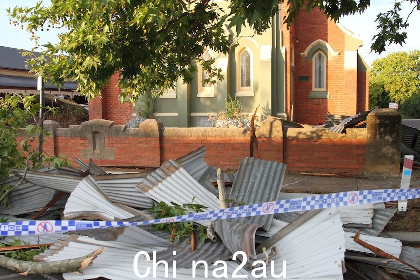 警察用胶带封住受损砖砌教堂前的一堆波纹铁皮。