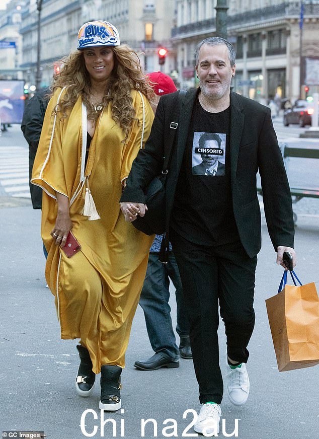 时尚达人:泰拉·班克斯 (Tyra Banks) 周四与男友路易斯·贝朗热-马丁 (Louis Bélanger-Martin) 在法国巴黎外出时身穿金色长袍,头戴蓝色镶边路易威登合身帽,彰显时尚气质