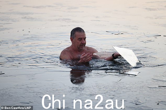 一名游泳者在海德公园的蛇形湖上破冰,该湖已结冰amid falling temperatures