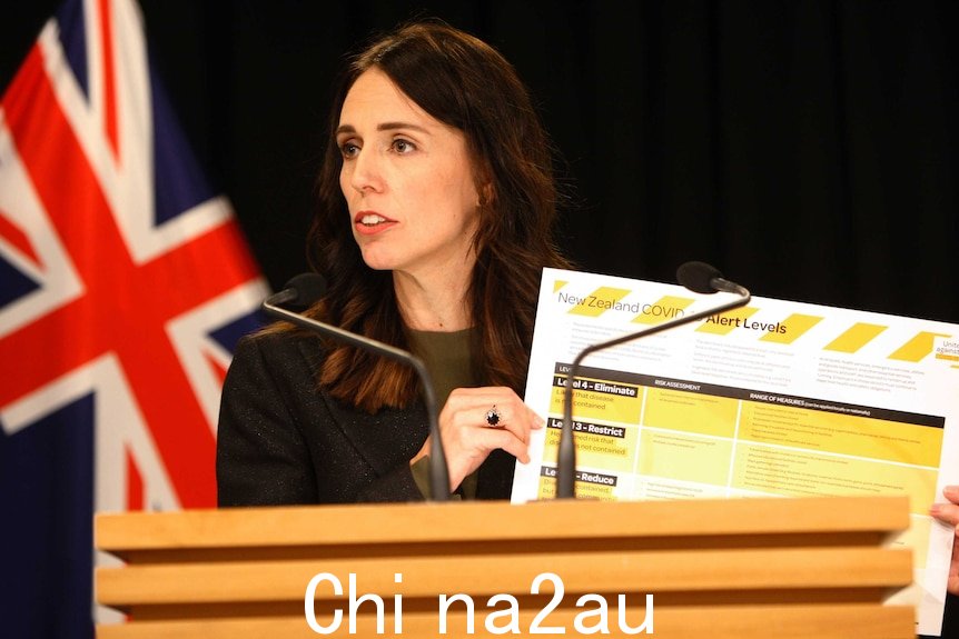 Jacinda Ardern 举着海报解释新西兰的冠状病毒警报系统