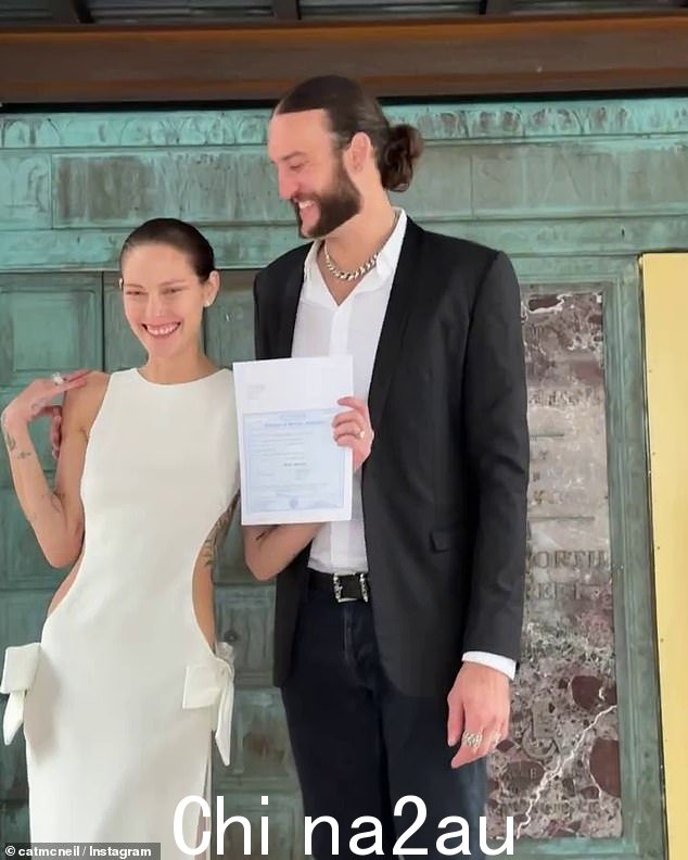 Cat 在法院外自豪地举着她的结婚证时满脸笑容