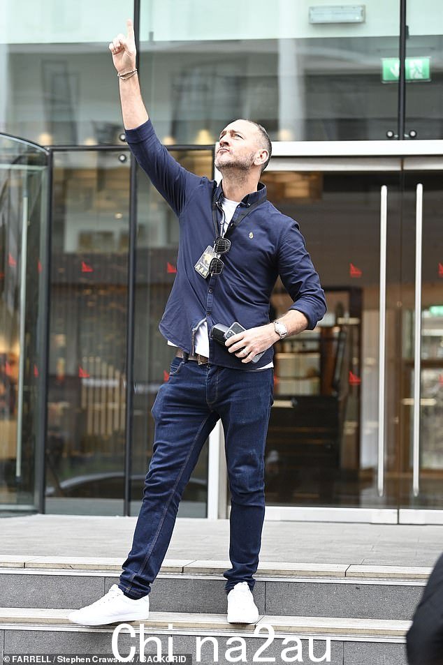 摆姿势!威尔·梅勒 (Will Mellor) 指着天空,他身穿海军蓝衬衫,外搭白色 T 恤