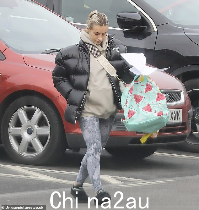 别致:Dani 裹身她穿着一件带衬垫的黑色 Prada 夹克,穿着米色连帽衫和灰色图案紧身裤,暖和起来