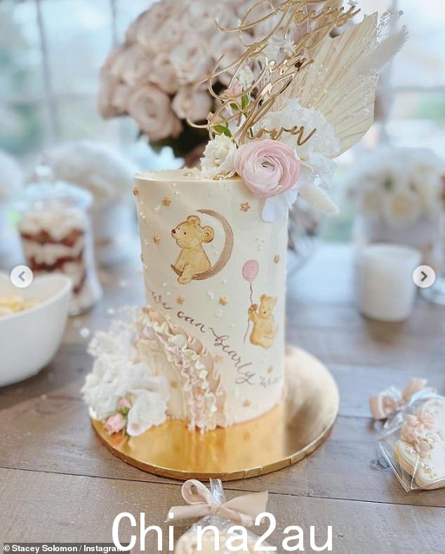 美味:那里这是一个漂亮的蛋糕,上面装饰着小熊、鲜花和饼干,上面印有“Stacey 的迎婴派对”字样